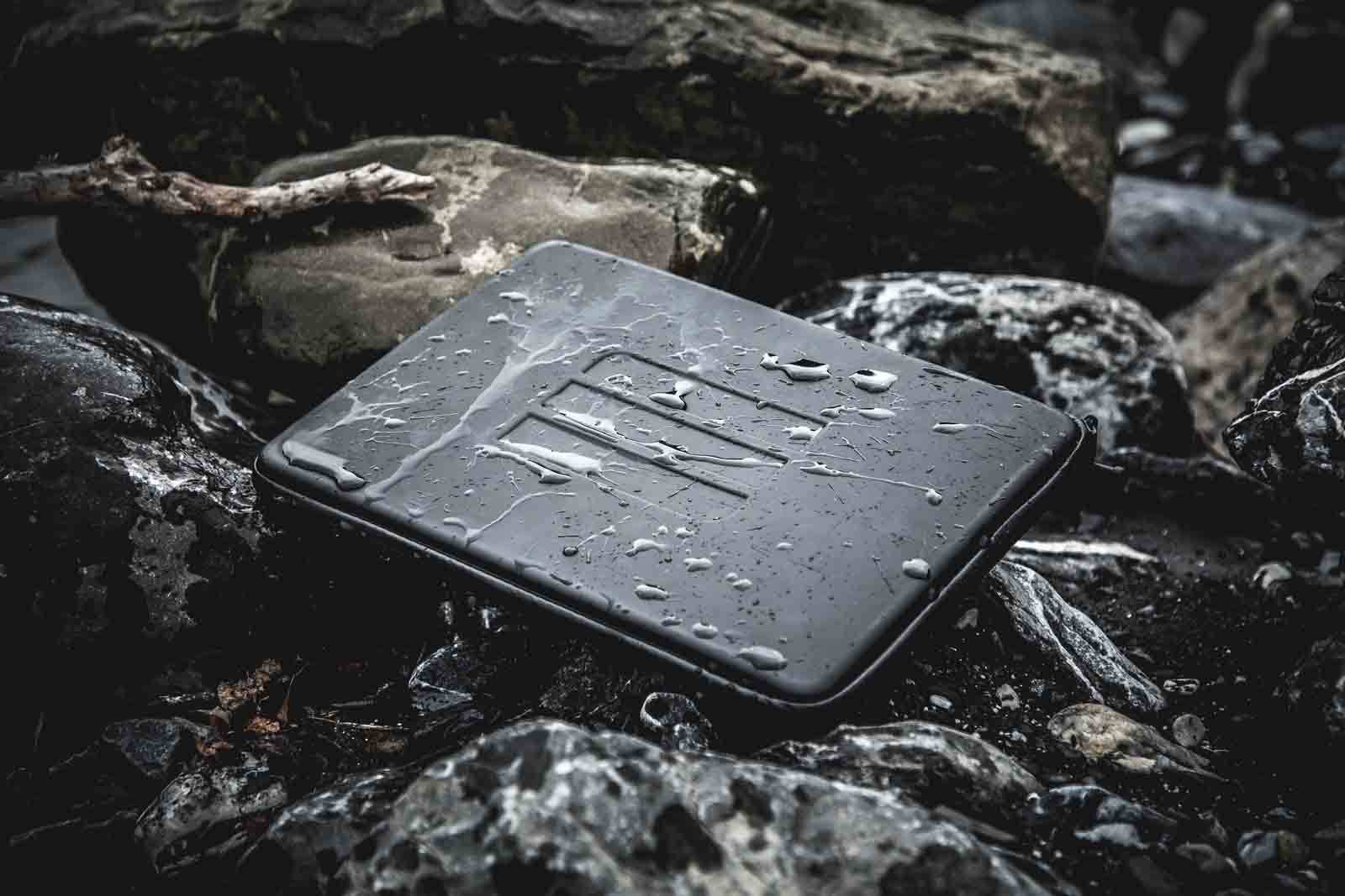 Wasserdichte Laptop-Tasche mit wasserabweisender Oberfläche auf nassen Felsen – robuster Notebook-Schutz für Outdoor-Abenteuer, Trekking, Camping, Reisen und anspruchsvolle Wetterbedingungen.